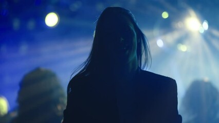 Attractive long haired woman wildly dancing at party. Silhouette against light background. Nightlife, modern music and entertainment concept.