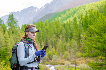 Woman uses mobile phone for navigation in the mountains. Empty space for text