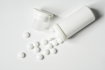 Fototapeta na wymiar White painkiller pills in jar on white backdrop. Health care and medicine concept
