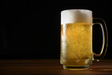 glass of cold beer on table dark background
