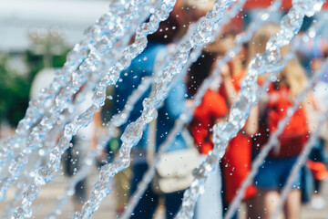 Spray fountain in the center of city with selective focus and blurred background. Running fountain with splashes and drops of water. Water jets in the fountain.