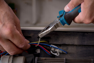 Old repairman repairing air-conditioner at workshop