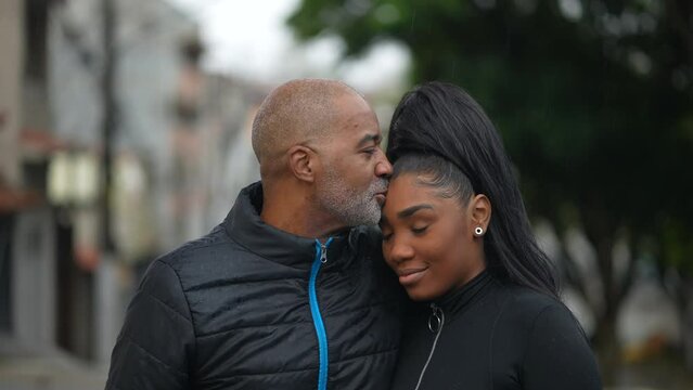 A black father kissing a teen daughter on forehead family love and affection