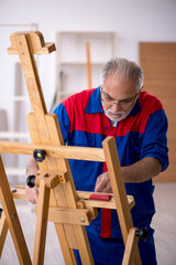Old male carpenter repairing drawing easel
