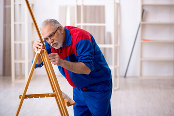 Old male carpenter repairing drawing easel