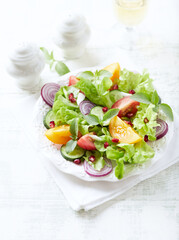 Salad with red and yellow Tomatoes and Pomegranate Seeds on bright wooden Background. Close up.	