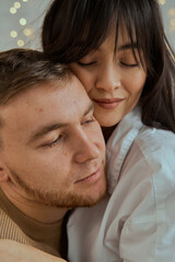 A girl and a guy sit on the bed hugging each other. Portrait of a young couple. The concept of love, relationships.