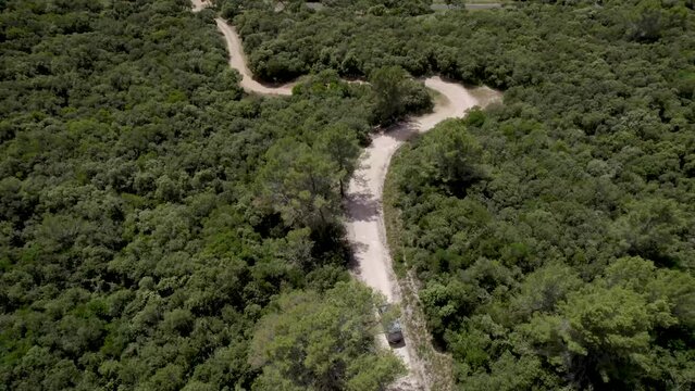 Mountain dirt road with van advancing near Gignac France, Aerial follow over shot