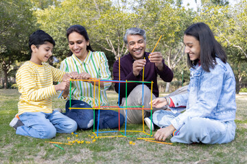 Happy parents with teenage daughter and son playing toys in park