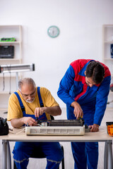 Two male repairmen repairing air-conditioner