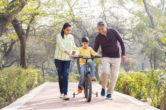 Parents teaching son riding bicycle at park