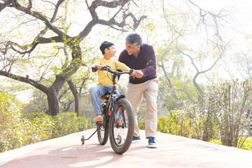 Fototapeta na wymiar Father teaching son riding bicycle at park