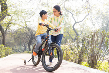 Mother teaching son riding bicycle at park