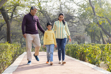 Obraz premium Happy family walking together holding hands at park