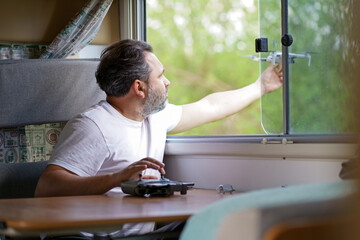 motorhome travel concept. Man controling a drone.a man controls a drone from the window of a...