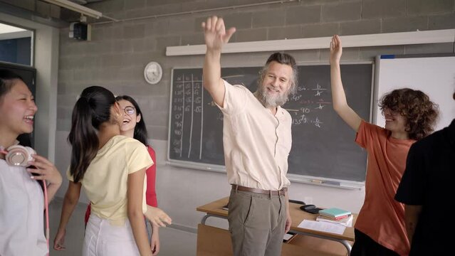 Group of happy students staking hand with the teacher. The professor look at camera.