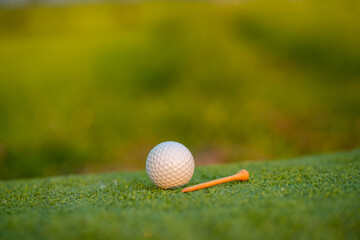 Golf ball is on tee at green lawn in a beautiful golf course with morning sunshine.Ready for golf in the first short.