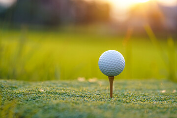 Golf ball is on tee at green lawn in a beautiful golf course with morning sunshine.Ready for golf in the first short.