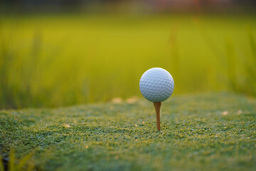 Golf ball is on tee at green lawn in a beautiful golf course with morning sunshine.Ready for golf in the first short.