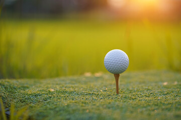 Golf ball is on tee at green lawn in a beautiful golf course with morning sunshine.Ready for golf in the first short.