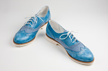 Blue imitation leather shoes laced with white laces. Close-up shot.