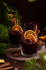 Fototapeta na wymiar Two glasses on a wooden tray with mulled wine. Berries, orange slices and cinnamon sticks decorate the glasses