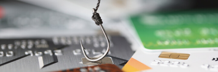 Fishing hook is hooked on plastic bank credit card closeup