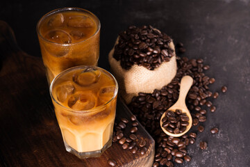 Coffee, iced latte in a glass Add milk or cream along with roasted coffee beans. Set on a wooden...