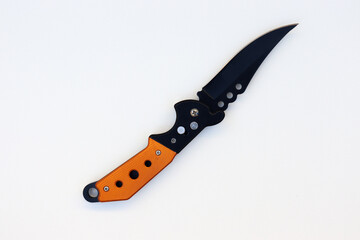 Isolated designer black knife with orange handle. Isolated knife with textured white background. knife on paper