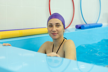A young girl is engaged in aqua yoga in the pool. Swimming for pregnant women. Health concepts