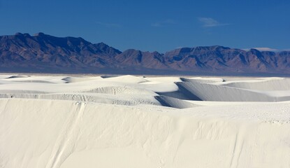 the vast expanses of  gypsum sand dunes against  the san andres mountains in white sands national park near alamogordo, new mexico