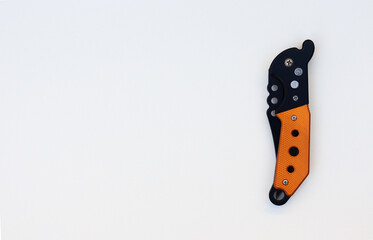 Isolated designer black folded knife with orange handle. Isolated knife with textured white background. knife on paper