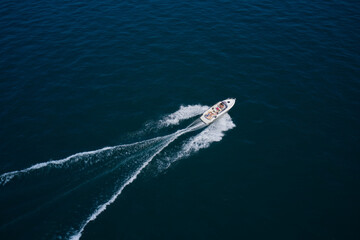Big white boat with people in motion in the sea top view. Boat drone view. Speedboat moves fast on the water view from above.