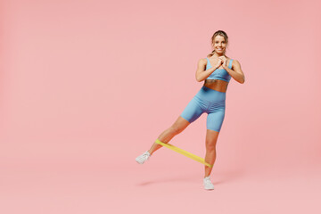 Full body young happy fun sporty athletic fitness trainer instructor woman wear blue tracksuit spend time in home gym use fitness rubber bands isolated on plain pink background. Workout sport concept.