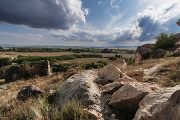 Stones of mountains against background of a flat steppe with a forest in Crimea on a summer day...