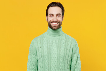 Young smiling happy caucasian european cheerful friendly man 20s wear mint knitted sweater looking camera isolated on plain yellow color background studio portrait. People lifestyle fashion concept