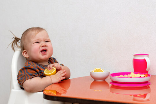 the child sits at the table and eats a lemon
