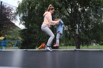 happy mother and daughter having fun together when playing on a trampoline.