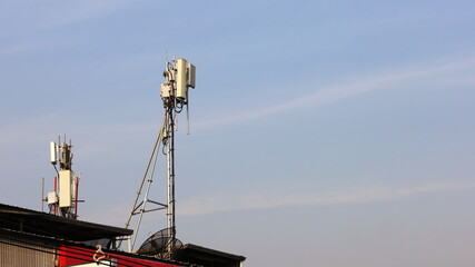Naklejka premium Microwave transmitter antennas on rooftop. Wireless communication transmitter or 4G and 5G mobile base stations on building roof on blue sky background with copy space. Selective focus