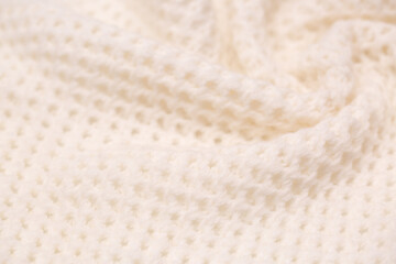 Knitted surface of woolen things as a background. Close-up of soft white texture of knitted patterns. Warm winter clothes. Background textile surface with copy space for text.