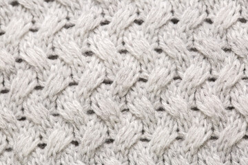 Knitted light surface of wool things as a background. Closeup of gray texture knitting patterns. Background with warm winter textile copy space.