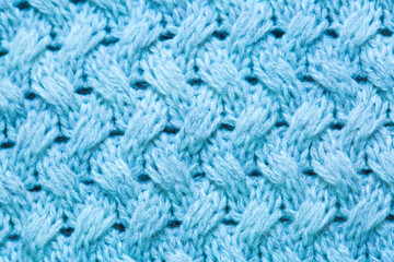 Knitted surface of woolen things as a background. Close-up of soft blue knitted patterns texture. Warm winter clothes. Background textile surface with copy space for text.