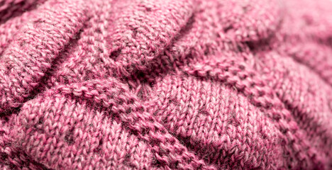 Knitted surface of woolen things as a background. Close-up soft pink color knitted patterns texture. Warm winter clothes. Background textile surface with copy space for text.