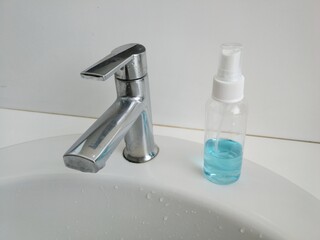 faucet and alcohol spray bottle in a bathroom
