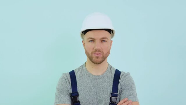 Serviceman in a helmett and overalls looking at camera on blue background