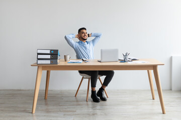 Smiling Arab man leaning back sitting at desk