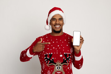 Smiling black man in santa hat pointing at smartphone