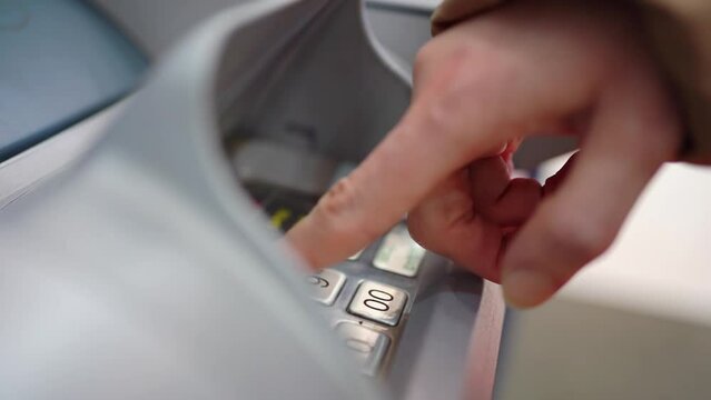 a woman's hand type the pin code or amount on the atm keyboard to withdraw money from the card. safety and reliability of money in the bank. bank card fraud.