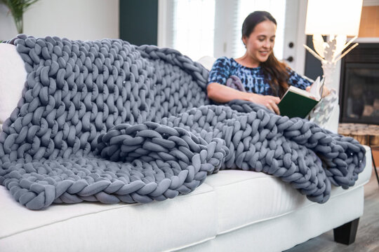 Woman Reads On White Couch With Weighted Blanket
