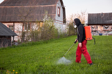 Farmers spraying pesticide on lawn field wearing protective clothing. Insecticide sprayer with a...